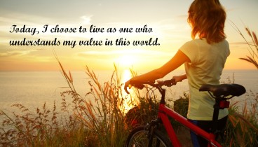 Young lady standing with bicycle on a sea coast and enjoying sunset